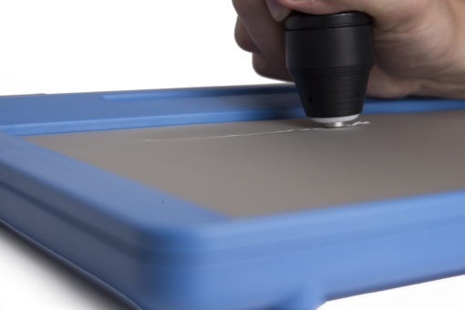 An inTACT Eraser is erasing a raised line on a blue inTACT sketchpad